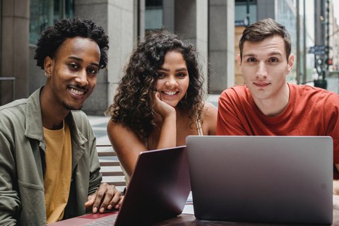 auf dem Bild sind 3 Studierende vor 2 Laptops zu sehen