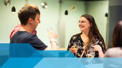 Auf dem Bild sind Alumni der Fakultät Maschinenwesen zu sehen, die ein Gespräch führen und Sekt trinken