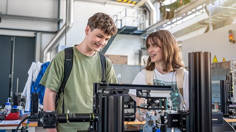  Zwei Schüler:innen der Junior-Ingenieur-Akademie während der Blockwoche auf dem Campus der TU Dresden an einem Prüfstand zur Untersuchung von Wasserstoffblasen. 