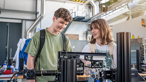  Zwei Schüler:innen der Junior-Ingenieur-Akademie während der Blockwoche auf dem Campus der TU Dresden an einem Prüfstand zur Untersuchung von Wasserstoffblasen. 