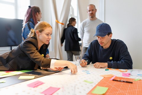 Auf dem Bild sind Mitarbeitende und Studierende des Technischen Designs der TUD zu sehen, die in einem Workshop zusammensitzen und brainstormen.