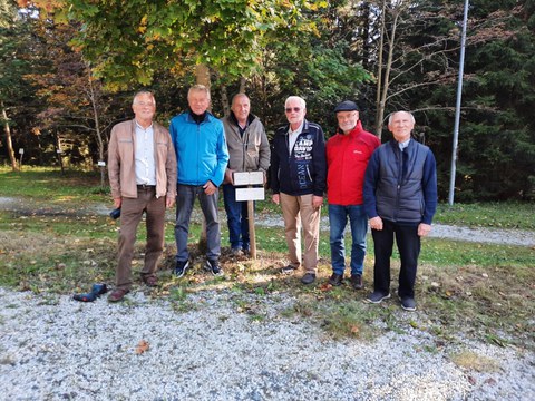 5 ältere Herren stehen unter Baum mit Schild zum Diplomjubiläum