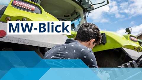 Junger Mann mit dem Rücken zur Kamera arbeitet an grünem Traktor