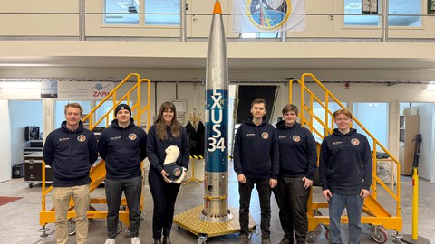 Das SHAMA-Team vor der vollständig integrierten Nutzlast der REXUS-34-Rakete. Die orangefarbenen Schutzhüllen umschließen bis zum Start die Experimentkomponenten. 