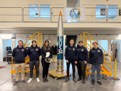 Das SHAMA-Team vor der vollständig integrierten Nutzlast der REXUS-34-Rakete. Die orangefarbenen Schutzhüllen umschließen bis zum Start die Experimentkomponenten. 