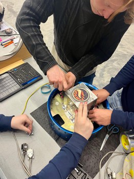 Gemeinsam montiert das SHAMA-Team das Elektronikgehäuse des Experiments während der Integrationsphase. 