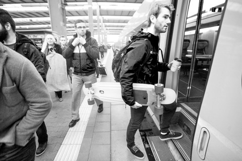 Ein junger Mann steigt in die U-Bahn ein und hält ein Skateboard unterm Arm.