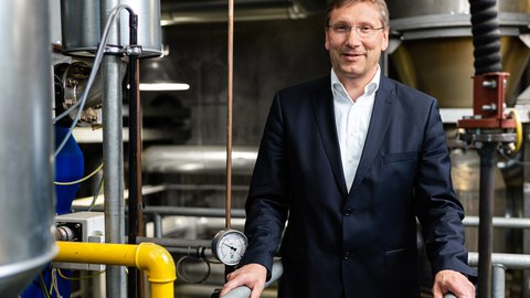 Foto von Professor Michael Beckmann vor dem Hintergrund einer virtuellen Stadtlandschaft 