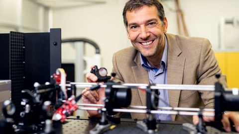 Foto von Professor Andrés Fabian Lasagni vor dem Hintergrund einer virtuellen Stadtlandschaft