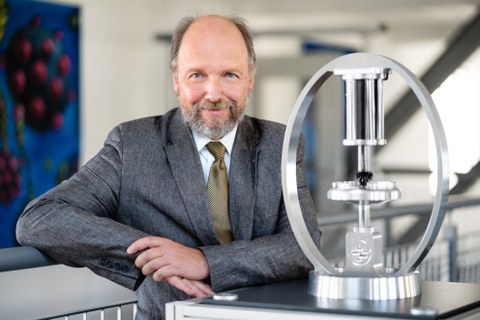 Foto von Professor Stefan Odenbach vor dem Hintergrund einer virtuellen Stadtlandschaft