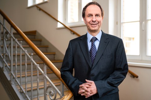 Foto von Professor Thomas Wallmersperger vor dem Hintergrund einer virtuellen Stadtlandschaft