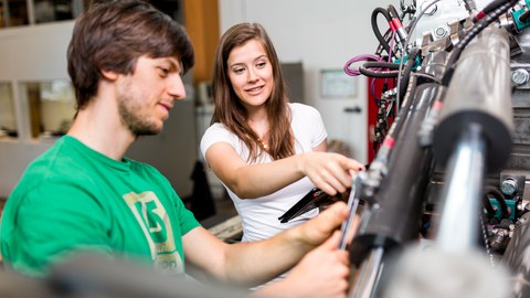 Foto: 2 Studierende kontrollieren die Anschlüsse von 2 Hydraulickzylindern am Hexapod-Prüfstand