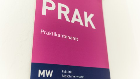 Foto: Hinweisschild mit PRAK (in sehr großer Schrift), darunter steht Prüfungsamt, am unteren Rand des Schildes steht MW Fakultät Maschinenwesen