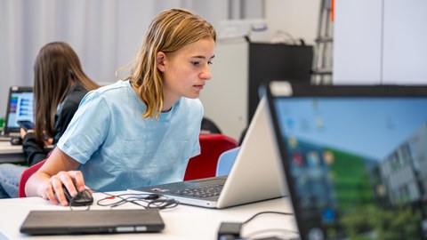 Auf dem Bild sind 2 Schülerinnen zu sehen, die an der Universität in den Fachbereich Informatik reinschauen