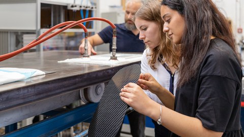 Auf dem Bild sind Studierende des Maschinenbaus an der TU Dresden zu sehen, die in einer Praxissituation im Leichtbau fotografiert worden