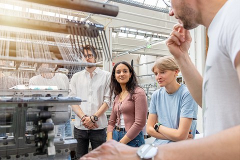 Auf dem Bild sind Studierende des Maschinenbaus an der TU Dresden zu sehen, die in einer Praxissituation in den Verarbeitungsmaschinen und Textilmaschinenbau fotografiert worden
