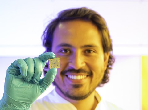 Auf dem Bild ist ein Mann zu sehen, der einen Mikrochip in die Kamera hält.