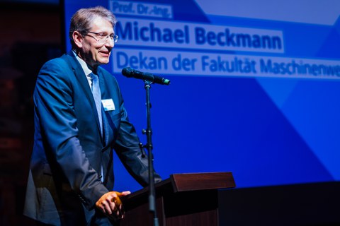 Der Dekan, ein großer älterer Mann in Anzug mit Brille am Rednerpult