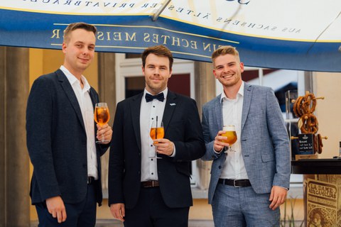 Drei Absolventen posieren mit Aperol Spritz-Gläsern