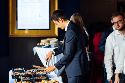 Junger Mann in Anzug bedient sich an Büffet