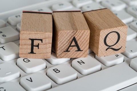 Auf dem Bild sind drei auf einer Tastatur liegende Buchstabenstempel mit den Buchstaben F A Q zu sehen.