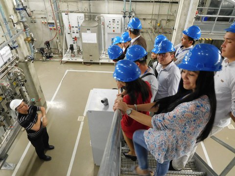 Das Foto zeigt eine Gruppe von usbekische Studierende am Gasturbinenkraftwerk im ZET. Sie stehen erhöht auf einer Treppe und schauen zu einem Mann hinunter, der etwas über den Ort erklärt.