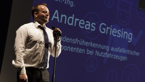 Dr. Andreas Griesing steht zum Science-Slam am Tag der Fakultät Maschinenwesen auf der Bühne am Mikrophon.