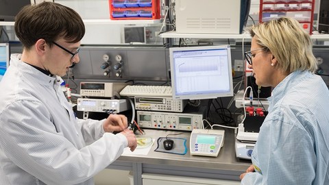 Das Foto zeigt Frau Staatsministerin Klepsch (rechts im Bild), die sich in den Laboren im Werner-Hartmann-Bau über das Projekt FlexEO informiert. Links im Bild sieht man einen jungen Mann, der der Staatsministerin etwas erklärt.