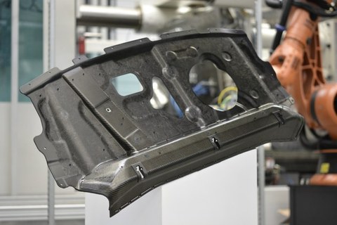 Das Foto zeigt ein graues Bauteil, welches mit der Spritzgieß-Fertigungstechnologie des „Schäumformens“ hergestellt wurde.