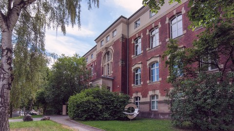 Außenansicht des Görges-Baus. Die Fassade besteht zu großen Teilen aus rotem Backstein und Sandsteinelementen. Vor dem Gebäude befindet sich eine metallische Skulptur.