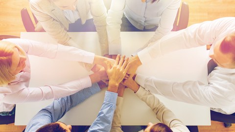 Nahaufnahme am Tisch von einem Team. Sitzen und halten die Hände auf der jeweils anderen.