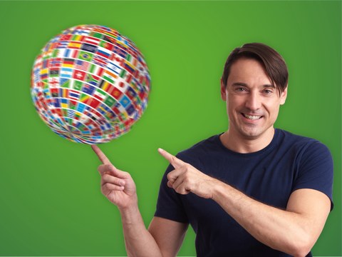 Image of a man pointing at a spinning globe made of many different countries' flags.