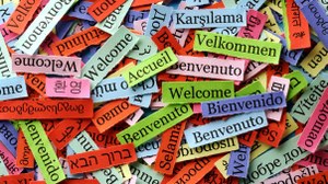 Das Foto zeigt viele kleine bunte Papierzettel. Auf ihnen steht das Wort "Willkommen" in verschiedenen Sprachen