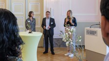 Die Programmkoordinatorin spricht ins Mikrofon neben Professor Tetzlaff und Professorin Böhm