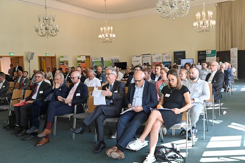 Blick in den Konferenzraum mit allen Sitzreihen und Personen