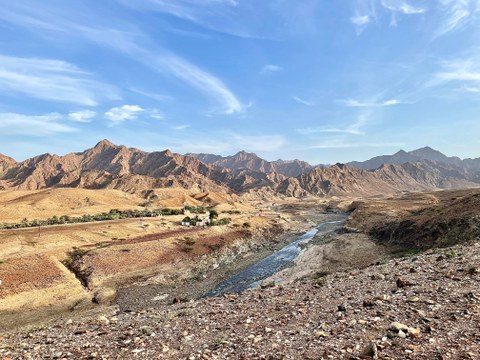 Landscape with reddish mountains and a small river.