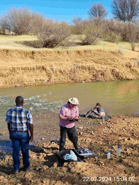 Two people taking water samples from a river in South Africa.