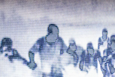 Screen photographed from close up. A shadowy image of people fleeing can be seen on the screen.