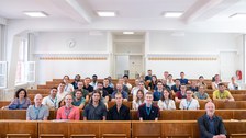 Gruppenbild der Teilnehmenden in einem Hörsaal auf Holzbänken sitzend.