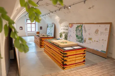 Blick in Ausstellungsraum mit Plakaten und Modellen