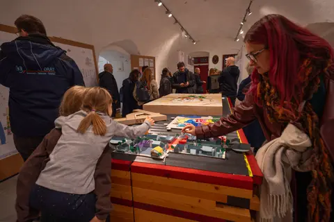 Kinder und Erwachsene untersuchen Modelle, die in Ausstellung zu sehen sind