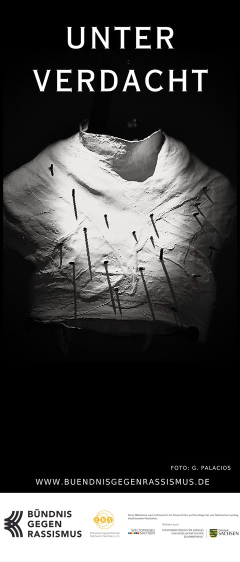 Das Bild zeigt eine weiß modellierte Torso-Skulptur, in die zahlreiche Nägel eingeschlagen sind, dramatisch aus dem Dunkel beleuchtet und überschrieben mit dem Titel „Unter Verdacht“.