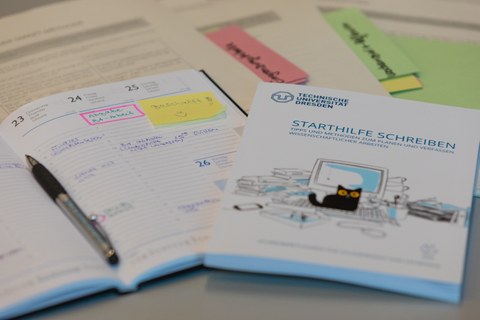Die broschüre Starthilfe Schreiben liegt neben einem Terminkalender, in dem die Abgabe einer Bachelorarbeit rosa markiert hervorgehoben ist.