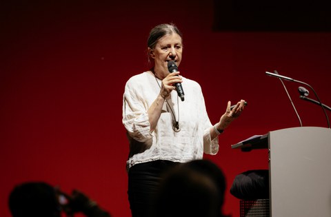 Eine Frau hält ein Mikrofon in der Hand und spricht hinein.
