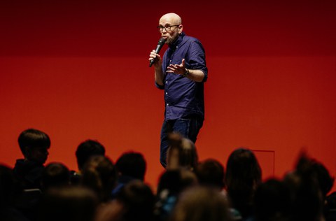 Ein Mann hält ein Mikrofon in der Hand und spricht hinein.