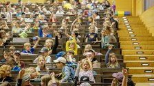 Viele Kinder sitzen in einem Hörsaal und melden sich.
