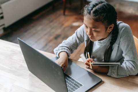 Ein Mädchen sitzt vor einem Laptop.