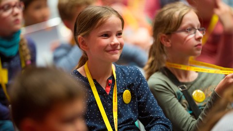 Das Foto zeigt ein lächelndes Mädchen im Hörsaal.