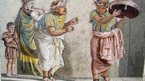 Das Bild zeigt ein Mosaik einer antiken Szene mit vier Personen, die mit antiken Instrumenten musizieren.
