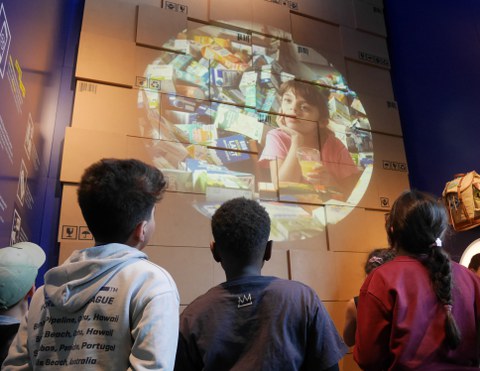 Das Foto zeigt drei Kinder von hinten, die sich eine Projektion in einer Ausstellung anschauen.